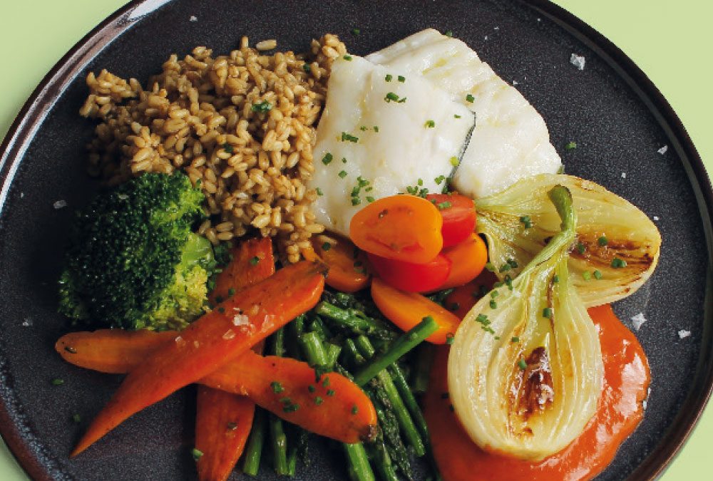 Bacalao asado con avena, salsa romesco, brócoli, cebolleta a la plancha, zanahorias, cherrys salteados y espárragos